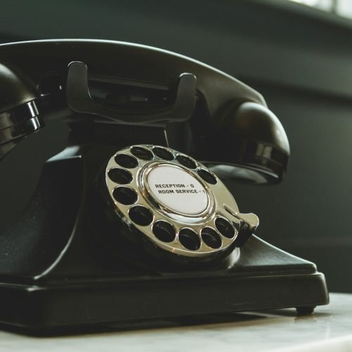 Classic black rotary phone on hotel reception desk, evoking nostalgia and vintage charm.