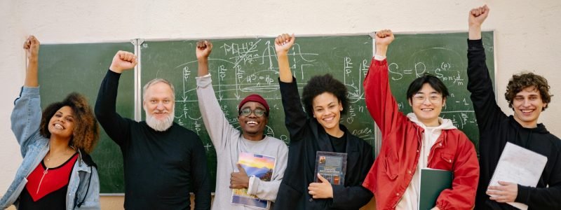 A cheerful group of diverse students and a teacher celebrating in front of a chalkboard full of equations.